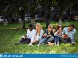 gruppo-razza-mista-di-studenti-che-si-siedono-insieme-sul-prato-inglese-verde-del-campus-universitario-134027624
